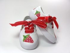 a pair of white shoes with red polka dots and strawberries tied to the side