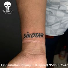 a man with a tattoo on his wrist that says skotar in black ink