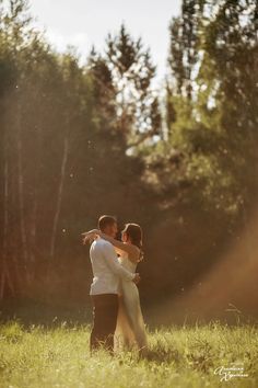 a man and woman hugging in the grass