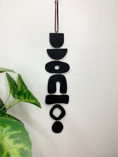 a black sign hanging on the wall next to a potted plant and a white wall