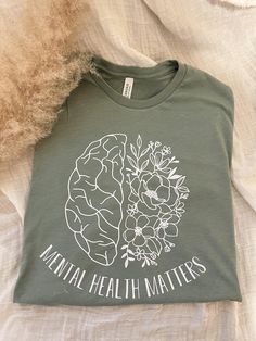 Your Mental Health MATTERS!  May is Mental Health Awareness month and Green is the color for Mental Health Awareness so this shirt is on a Heathered Sage Green Bella Canvas Tee also available in Sand (Gildan Shirt) with black vinyl.  matching Iced coffee Cup is also available here:  https://www.etsy.com/listing/1141509276/mental-health-matters-beer-can-glass?ref=listings_manager_grid Made using a heat press and premium vinyl Sizes are unisex so order true to size or go up a size for an oversized Mental Health T Shirts, Mental Health Awareness Month, Iced Coffee Cup, Awareness Shirt, Bella Canvas Tees, Young T, Tshirt Ideas, Mental Health Matters, Health Matters