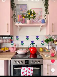 a kitchen with pink cabinets and flowers on the backsplash, potted plants in vases