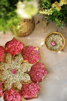 an arrangement of pink and white flowers on a table with other items in the background