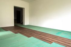 an empty room with hard wood flooring and green mats on the floor in front of it