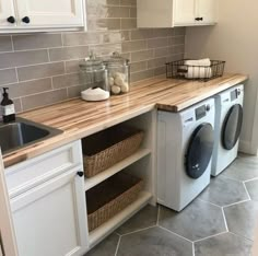 a washer and dryer sitting in a kitchen next to a counter with baskets on it