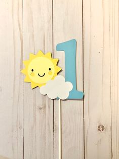 a cake topper with the number one on it and a sun in the sky