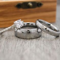 two wedding rings sitting on top of a wooden table