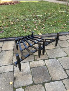 a metal bed frame sitting on top of a brick walkway in front of a grassy field