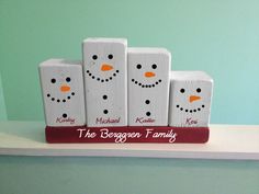 four wooden blocks with snowmen painted on them sitting on a shelf in front of a green wall