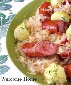 a green plate topped with potatoes and sausage