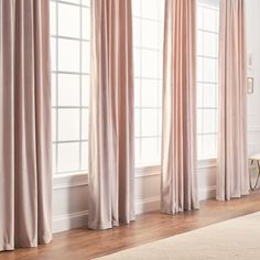 a living room filled with lots of pink curtains next to a white chair and window