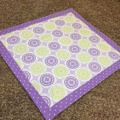 a purple and green bandana laying on top of a carpeted floor with polka dots