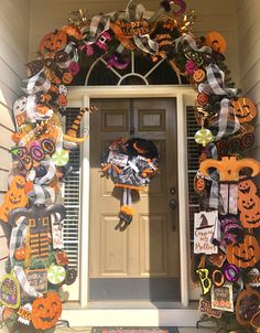 a front door decorated for halloween with pumpkins and other decorations on the outside wall