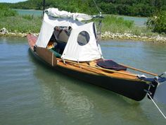 a small boat with a tent attached to it's front end in the water