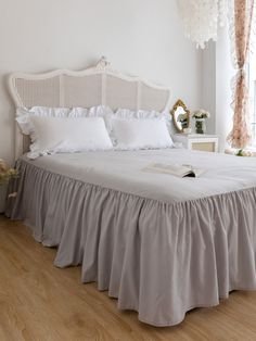 a bed with white sheets and ruffled bedspread