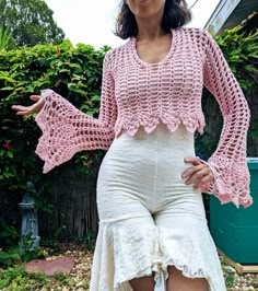 a woman wearing a pink crochet top and white skirt posing for the camera