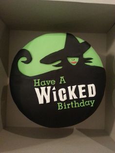 a black and green cake in a box with the words have a wicked birthday written on it