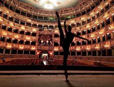 a person standing in the middle of an empty auditorium with their arms up and legs crossed