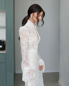 a woman in a white lace dress is looking down at her hand on her hip