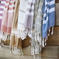 several different colored towels hanging on a wooden wall