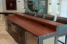 a large kitchen with an island made out of wood and stainless steel barstools