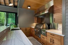 a kitchen with marble counter tops and stainless steel oven hoods, windows, and wood paneling