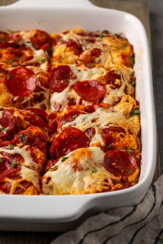 pepperoni and cheese pizza in a white casserole dish on a wooden table