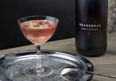 a drink sitting on top of a metal tray next to a bottle