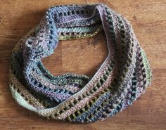 a multicolored crocheted scarf sitting on top of a wooden table