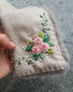 a hand is holding a small purse with flowers on the front and side, which are embroidered onto it