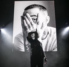 a man holding his hands to his face while standing in front of a large screen