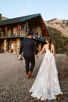 a bride and groom walking hand in hand towards the mountain house at their wedding reception