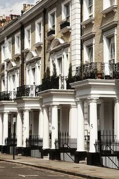 row of white houses with balconies and wrought iron railings on the street