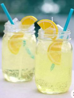 two mason jars filled with lemonade sitting on top of a white table next to each other