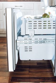 an open refrigerator in a white kitchen with wood flooring and wooden counter top space