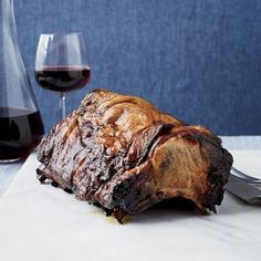 a piece of meat sitting on top of a table next to a glass of wine