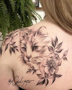 the back of a woman's shoulder with a cat and flowers tattoo on it