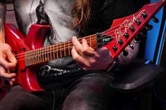 a person sitting in a chair playing an electric guitar with their hands on the strings