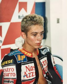 a shirtless man sitting in front of a red and white wall