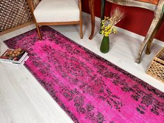 a bright pink rug is on the floor next to a chair and table with flowers