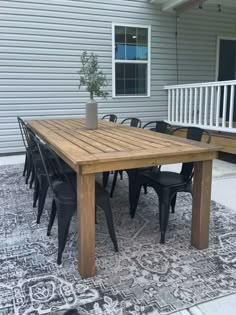 a wooden table sitting on top of a rug in front of a house next to a patio