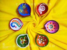 four colorful painted bowls sitting on top of a yellow cloth