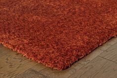 an orange rug on the floor with wood floors