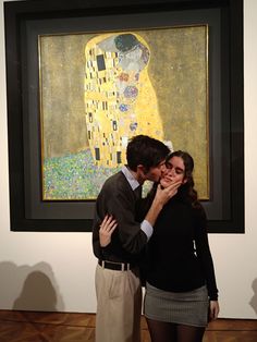 a man and woman standing next to each other in front of a painting