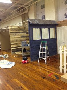 the inside of a building with wood floors and ladders on each side of it