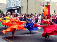 several women in colorful dresses are dancing on the street