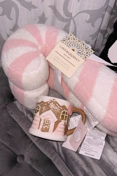 a pink and white striped stuffed animal next to a cup with a house on it