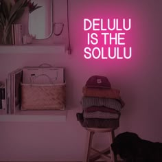 a pink neon sign that says delu is the soulu in front of a chair