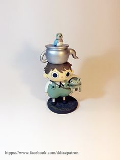 a figurine with a pot on top of it's head holding a lizard