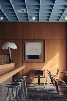 an empty room with chairs and stools in front of a painting on the wall